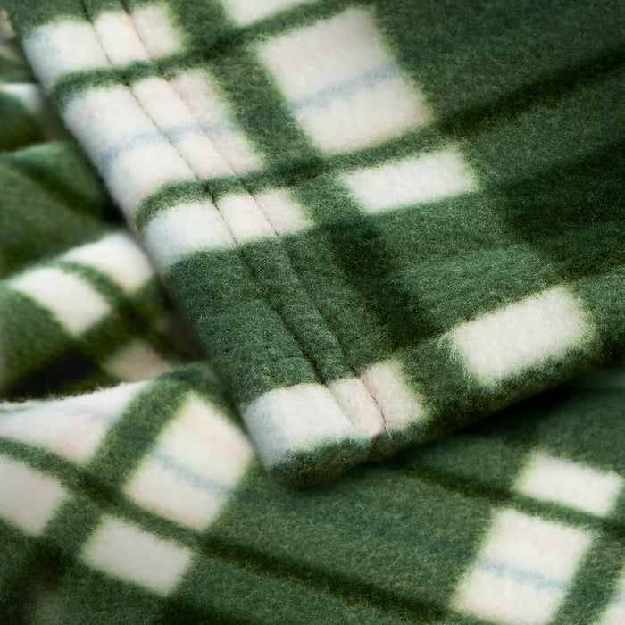 Close-up of IKEA ODENSLÄTA green check blanket showing soft texture, neatly folded