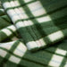 Close-up of IKEA ODENSLÄTA green check blanket showing soft texture, neatly folded