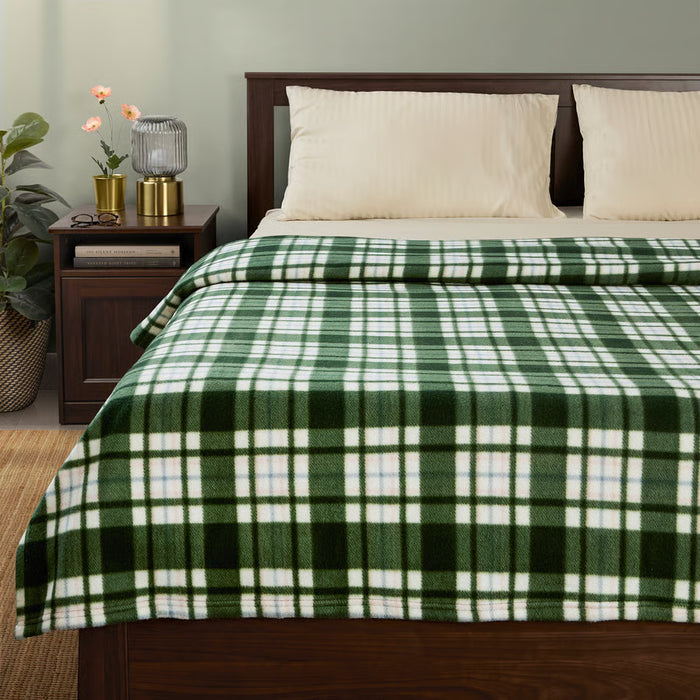 Cosy IKEA ODENSLÄTA dark green check blanket styled on a made bed in a bedroom