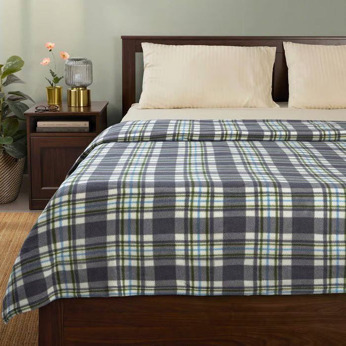 IKEA ODENSLÄTA check pattern blanket almost covering a bed styled with pillows and a plant