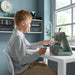 Boy studying at desk with laptop beside IKEA ÖVNING organiser and stationery