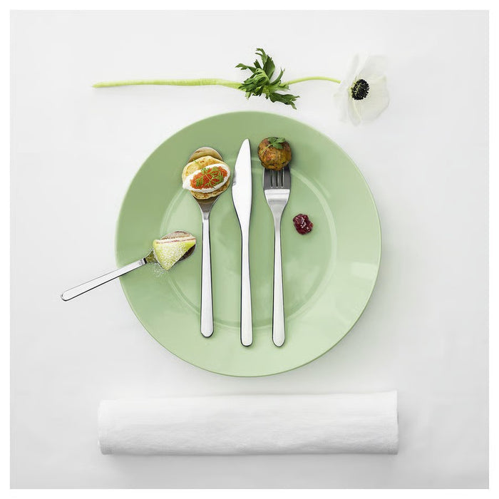 "A light green, glossy ceramic plate with a smooth surface and slightly raised edges, placed against a white background.