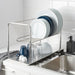  IKEA ORDNING silver dish drainer holding white plates blue bowls and glasses over sink