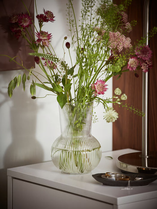 IKEA PÅDRAG clear glass vase with colourful flowers on white cabinet showing ribbed vertical lines