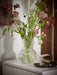 IKEA PÅDRAG clear glass vase with colourful flowers on white cabinet showing ribbed vertical lines