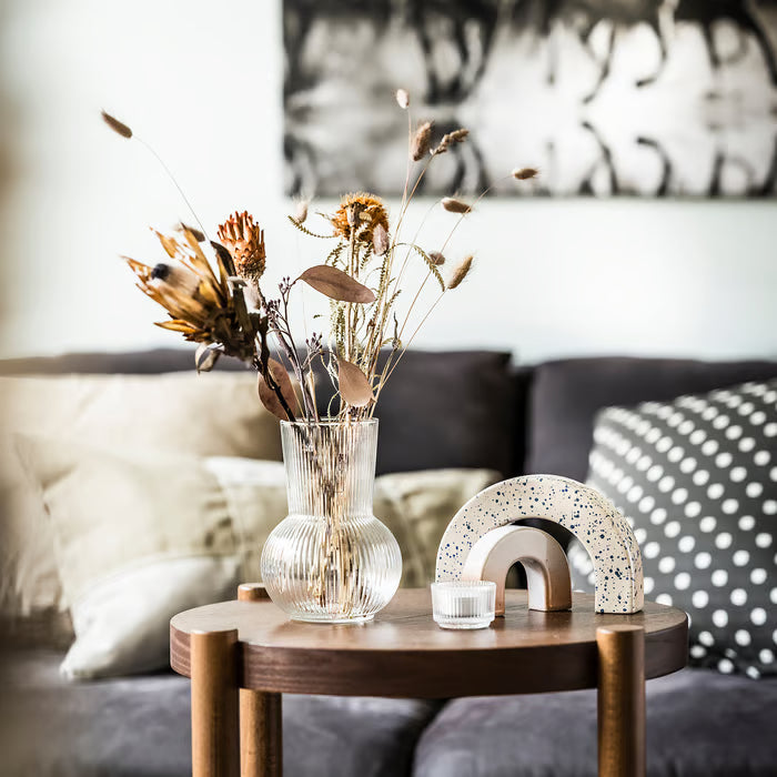 IKEA PÅDRAG clear glass vase with dried flowers on wooden side table in living room with dark sofa