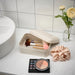 IKEA PLOGFÅRA light beige metal box on bathroom counter holding makeup brushes and sponge