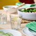 IKEA POKAL clear glass filled with lemon water on dining table with plates and salad bowl