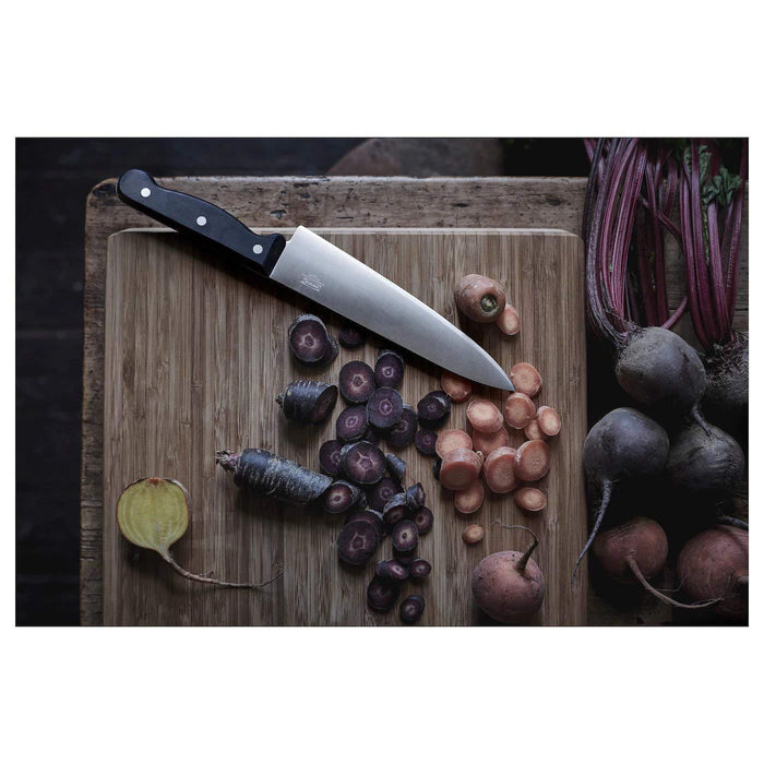 Wooden cutting board with vegetables and a knife on a dark background