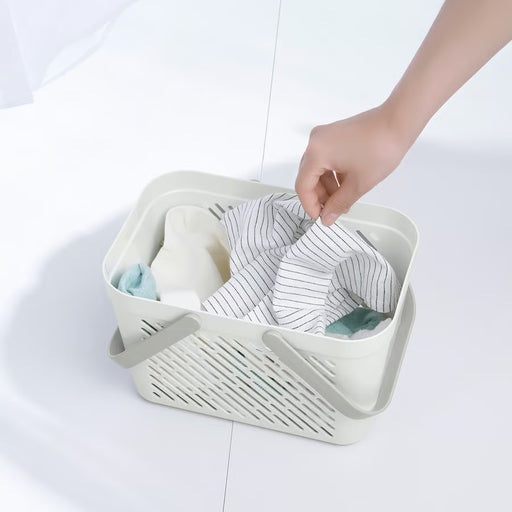 Person placing toiletry bottles into IKEA RÅNEN white shower basket with side ventilation holes