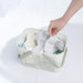Person placing toiletry bottles into IKEA RÅNEN white shower basket with side ventilation holes