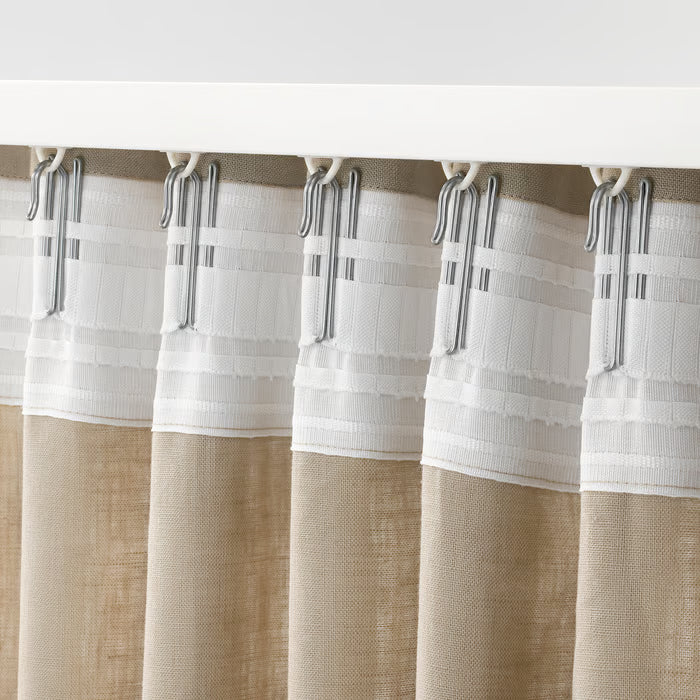 Close-up of an IKEA RIKTIG steel curtain hook showing the pleating hook design