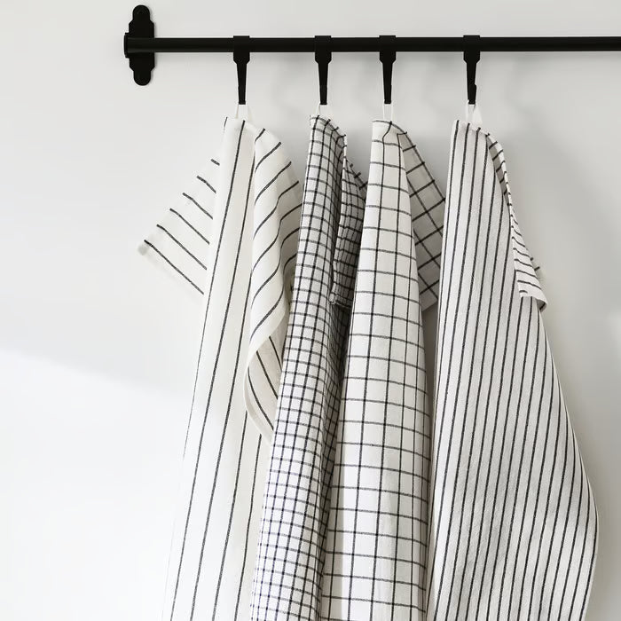 Four IKEA RINNIG kitchen towels in mixed patterns hanging from black rod in styled kitchen setting