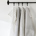 Four IKEA RINNIG kitchen towels in mixed patterns hanging from black rod in styled kitchen setting