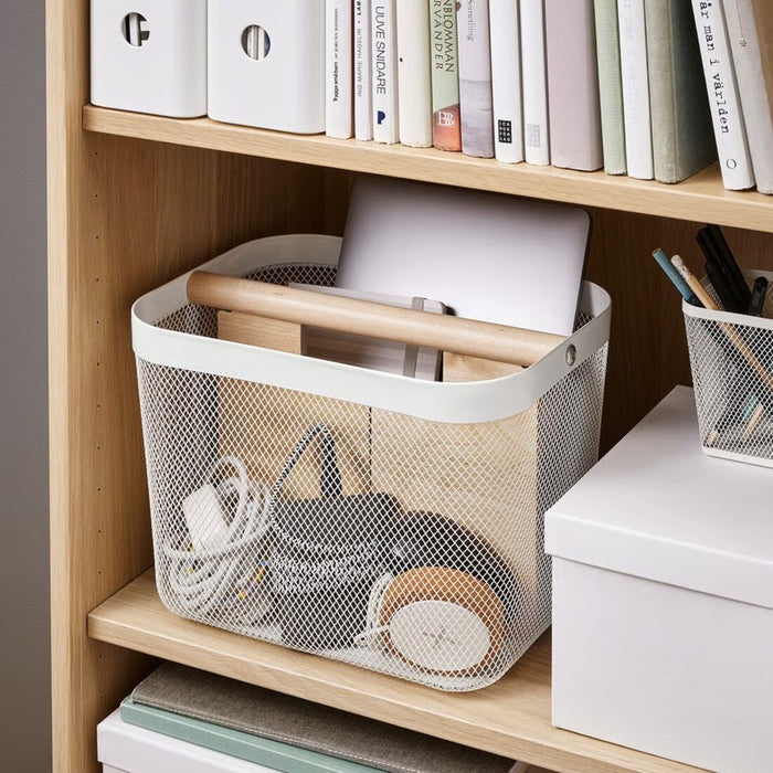 Storage basket with handles on a wooden shelf with books and office supplies.