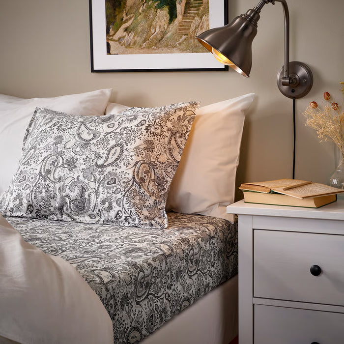 IKEA RODGERSIA grey white flat sheet on neatly made double bed with decorative pillows and bedside lamp