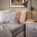 IKEA RODGERSIA grey white flat sheet on neatly made double bed with decorative pillows and bedside lamp
