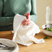 Person holding IKEA RÖDSPÄTTA white tea towel near kitchen table with bowls and utensils