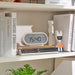 Digital clock on a shelf with books and decorative items