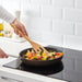 Colourful vegetables being cooked in a non-stick pan using IKEA RÖRT wooden fork on induction stove