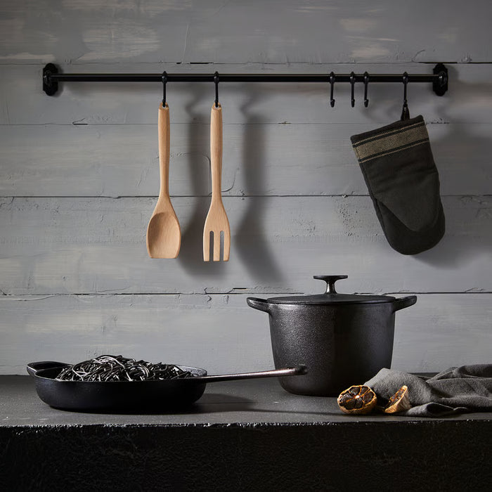  IKEA RÖRT wooden fork displayed with black cookware, oven mitt and citrus on weathered wall hooks