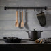  IKEA RÖRT wooden fork displayed with black cookware, oven mitt and citrus on weathered wall hooks