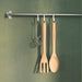  IKEA RÖRT wooden fork hanging on a hook alongside spoon and strainer against a green wall