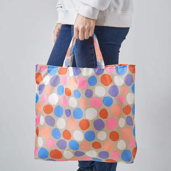 Person holding IKEA ROMELSÖN colourful polka dot tote bag by the handles