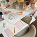 IKEA ROMELSÖN case beside notepads, pens and flowers on a white desk workspace
