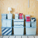 IKEA RYKTA grey-blue storage boxes multiple sizes stacked together on light wood surface showing size range