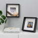 IKEA SANNAHED black frame on a living room wall with a 13x13 cm art print and white mount