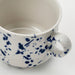 "A ceramic mug with a white base and a pattern of blue splatters and dots, featuring a sturdy handle and a smooth interior, designed for coffee, tea, or other beverages