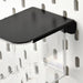 Close-up of IKEA SKÅDIS clear container with black lid mounted on white pegboard