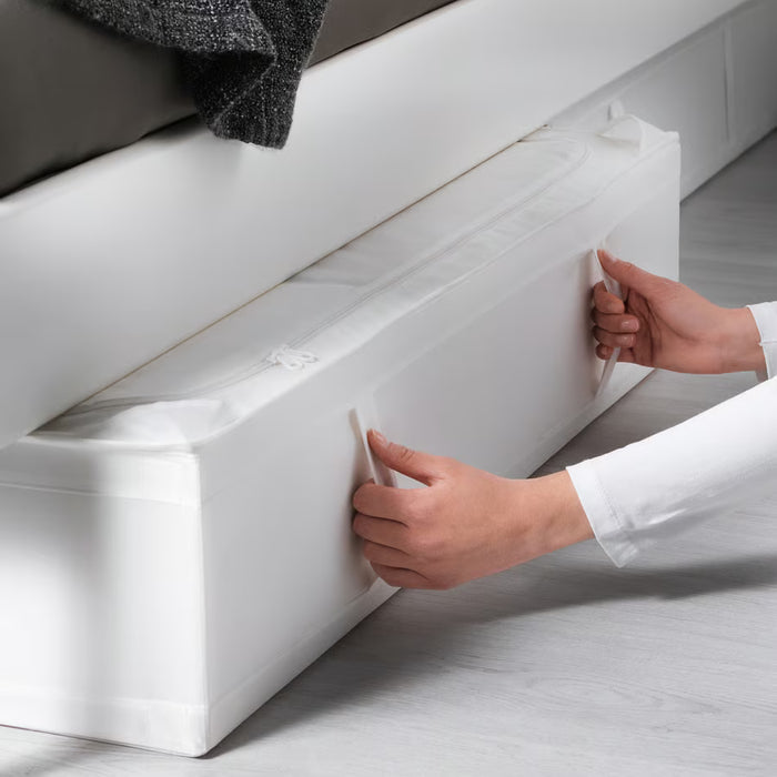 Person sliding IKEA SKUBB white storage case under a bed showing slim profile and easy-grip handles