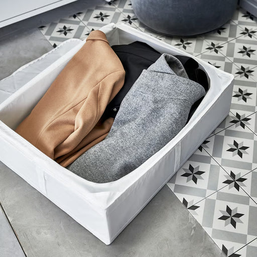 IKEA SKUBB white storage case open showing folded beige and grey clothes on tiled floor