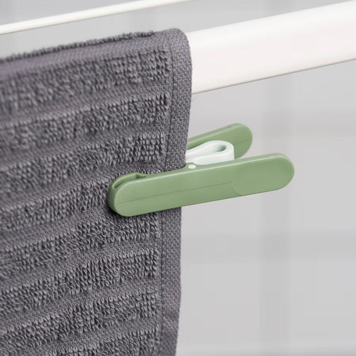 IKEA SLIBB clothes peg in green plastic with a rounded grip and firm spring, used for securing clothes to a drying line.