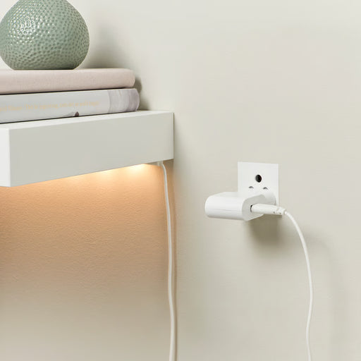 IKEA SMÅHAGEL white USB charger powering LED shelf light with books and vase in home setting