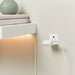 IKEA SMÅHAGEL white USB charger powering LED shelf light with books and vase in home setting