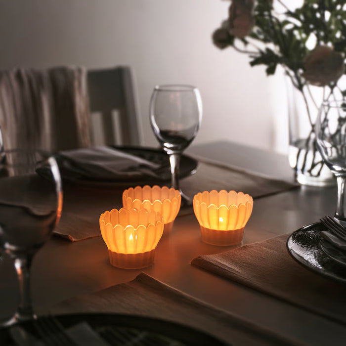 IKEA SMÅNÄCKROS white tealight holder glowing with lit candle, side view
