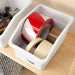 White SOCKERBIT box labelled tape holding red, white and beige tape rolls on wooden surface