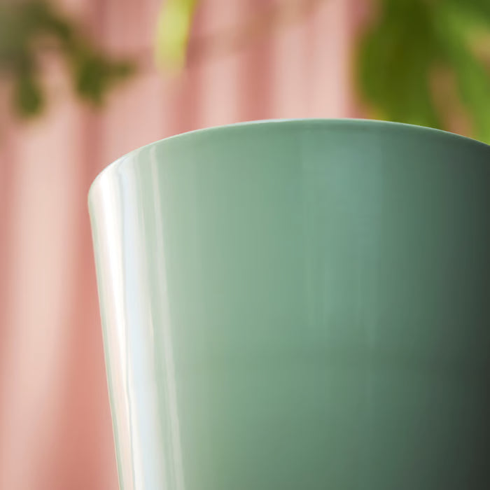 Close-up of IKEA SOJABÖNA bright light green plant pot smooth finish against colourful background