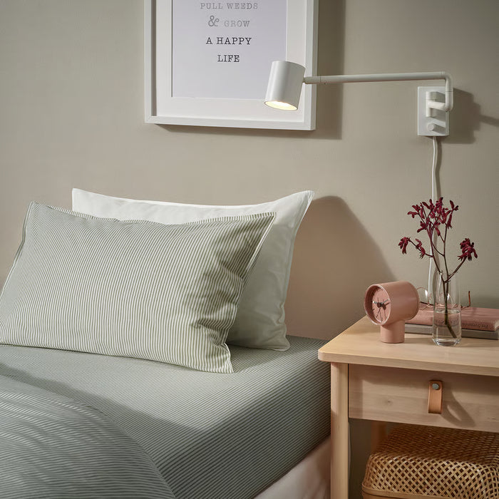 IKEA SOLFIBBLA striped bedding on a made bed with bedside table, lamp and flowers in a bedroom