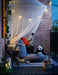 IKEA SOLIG net canopy over outdoor patio seating with cushions and evening string lights