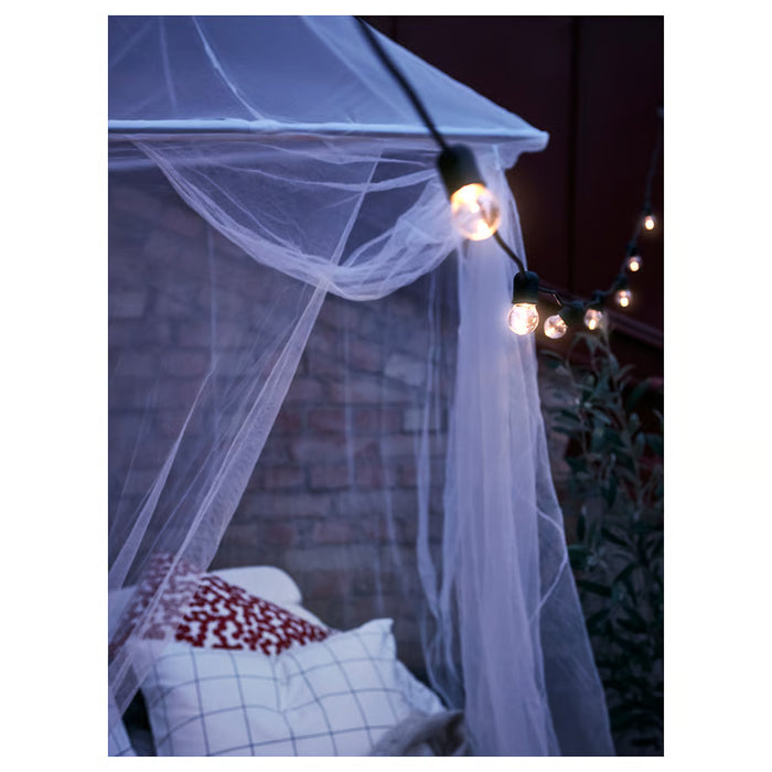 IKEA SOLIG net canopy over bed at night with warm string lights for a calm retreat