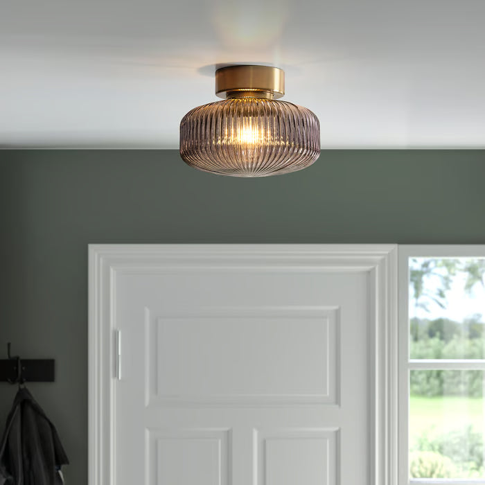 IKEA SOLKLINT brass ceiling lamp close-up showing grey glass shade and decorative shadow pattern on ceiling