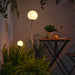 IKEA SOLVINDEN lit spherical outdoor light glowing among green ferns on garden pole