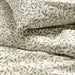 Stacked IKEA SORGMANTEL white duvet cover and pillowcases with subtle green leaf pattern fabric texture