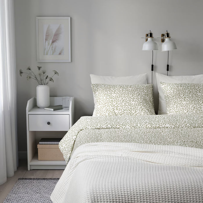 IKEA SORGMANTEL leaf pattern bedding on a minimalist bed with nightstands, dried flowers and wall lamps
