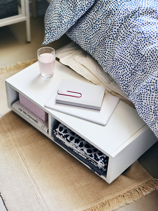 IKEA SORTSÖ natural cotton rug on floor beside bed with blue patterned bedding and white side table