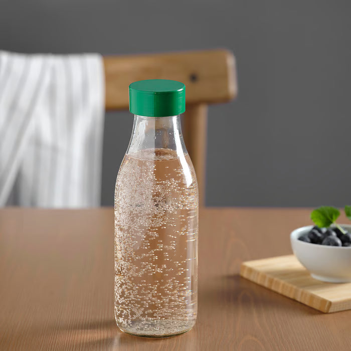 IKEA SPARTANSK clear glass water bottle green standing on a wooden table